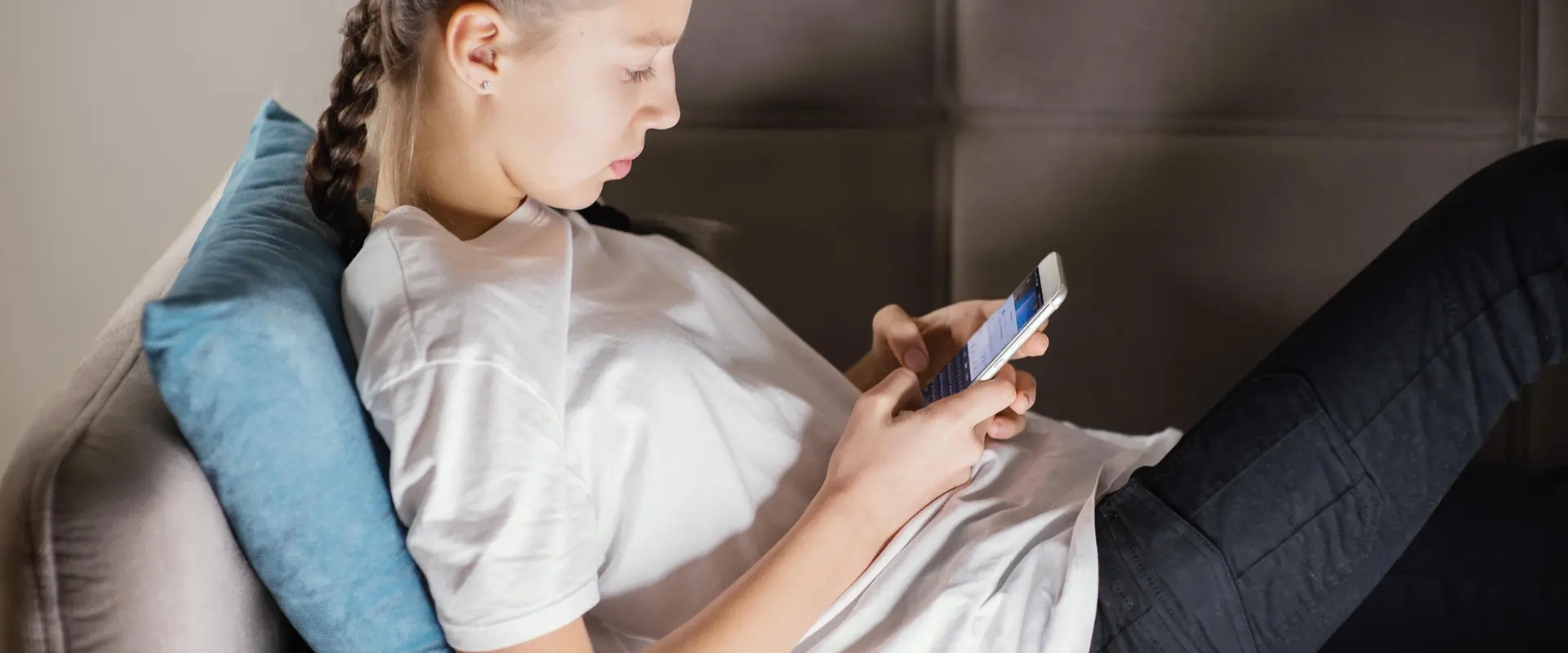 Teenager liegt auf dem Sofa und schaut etwas im Smartphone nach