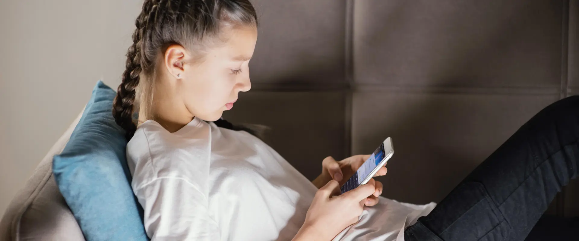 Teenager liegt auf dem Sofa und schaut etwas im Smartphone nach