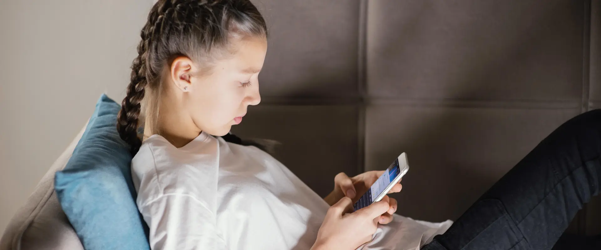 Teenager liegt auf dem Sofa und schaut etwas im Smartphone nach