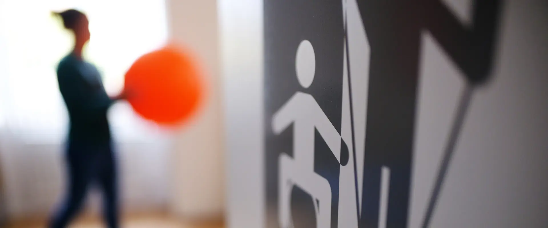 MZEB in Braunschweig. Blick in die Physiotherapie eine Frau hält einen großen orangenen Ball